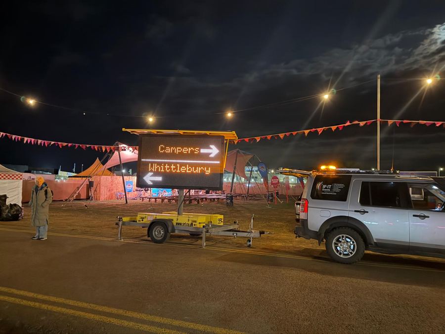 Illuminated sign directing campers, next to an IF-IT Events 4x4 at night